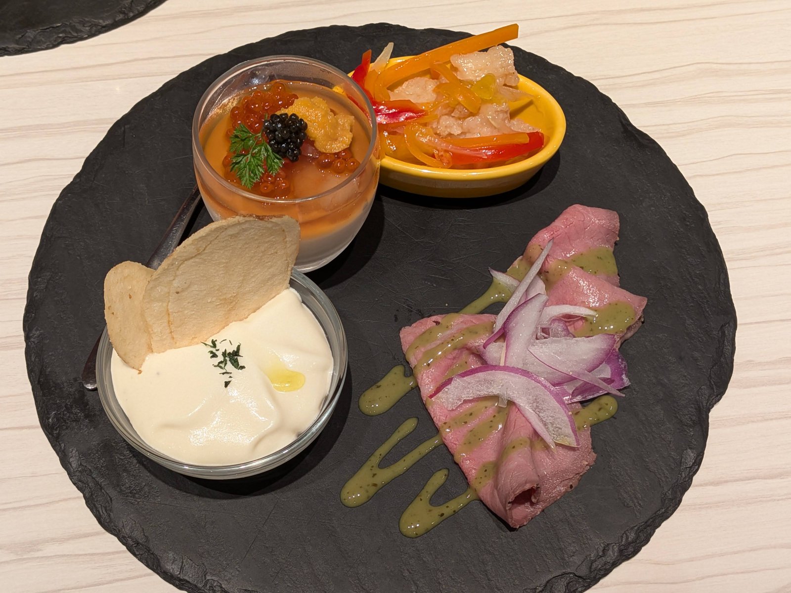 4種類の冷前菜の盛り合わせ。ジュレ、ムース、ローストビーフ、おまかせ前菜が黒い丸皿に並ぶ