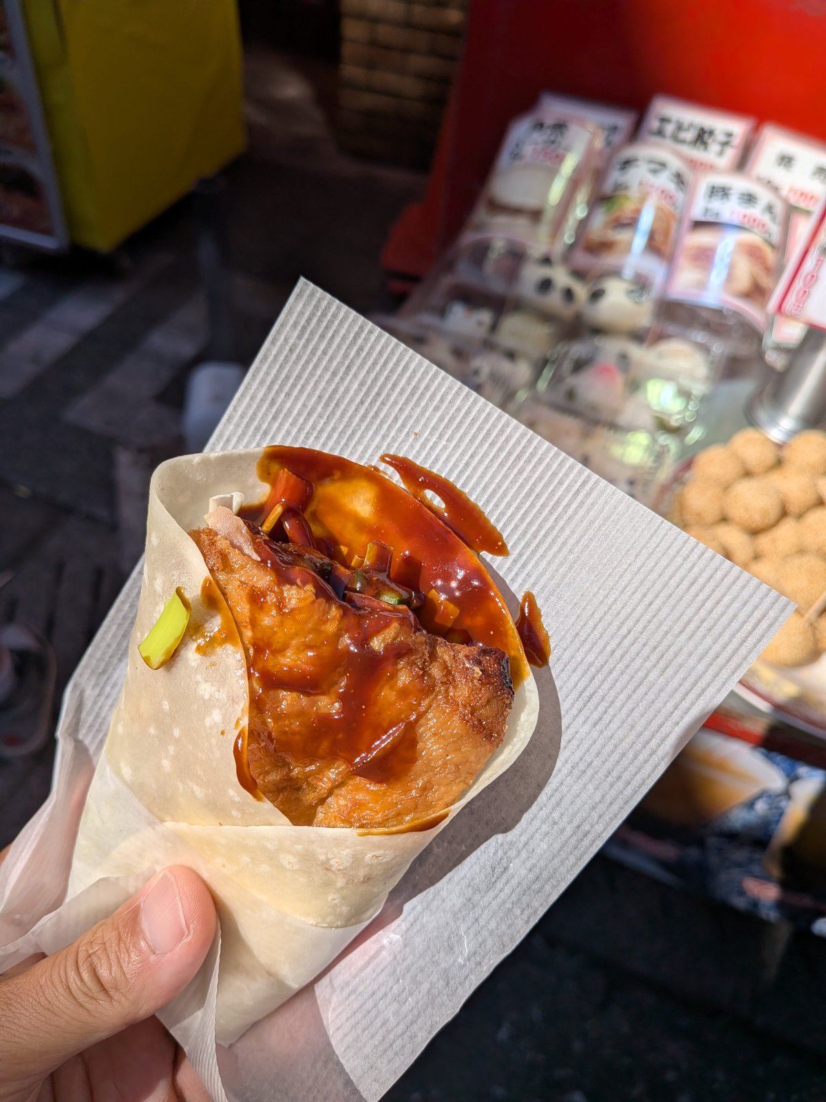 北京ダックを薄い皮で巻いた食べ歩き用の一品。甘辛そうなタレがかかっている