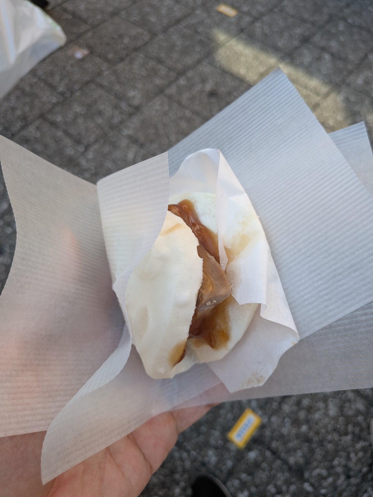 豚角煮を挟んだ白い蒸しパン。紙に包まれて手に持っている