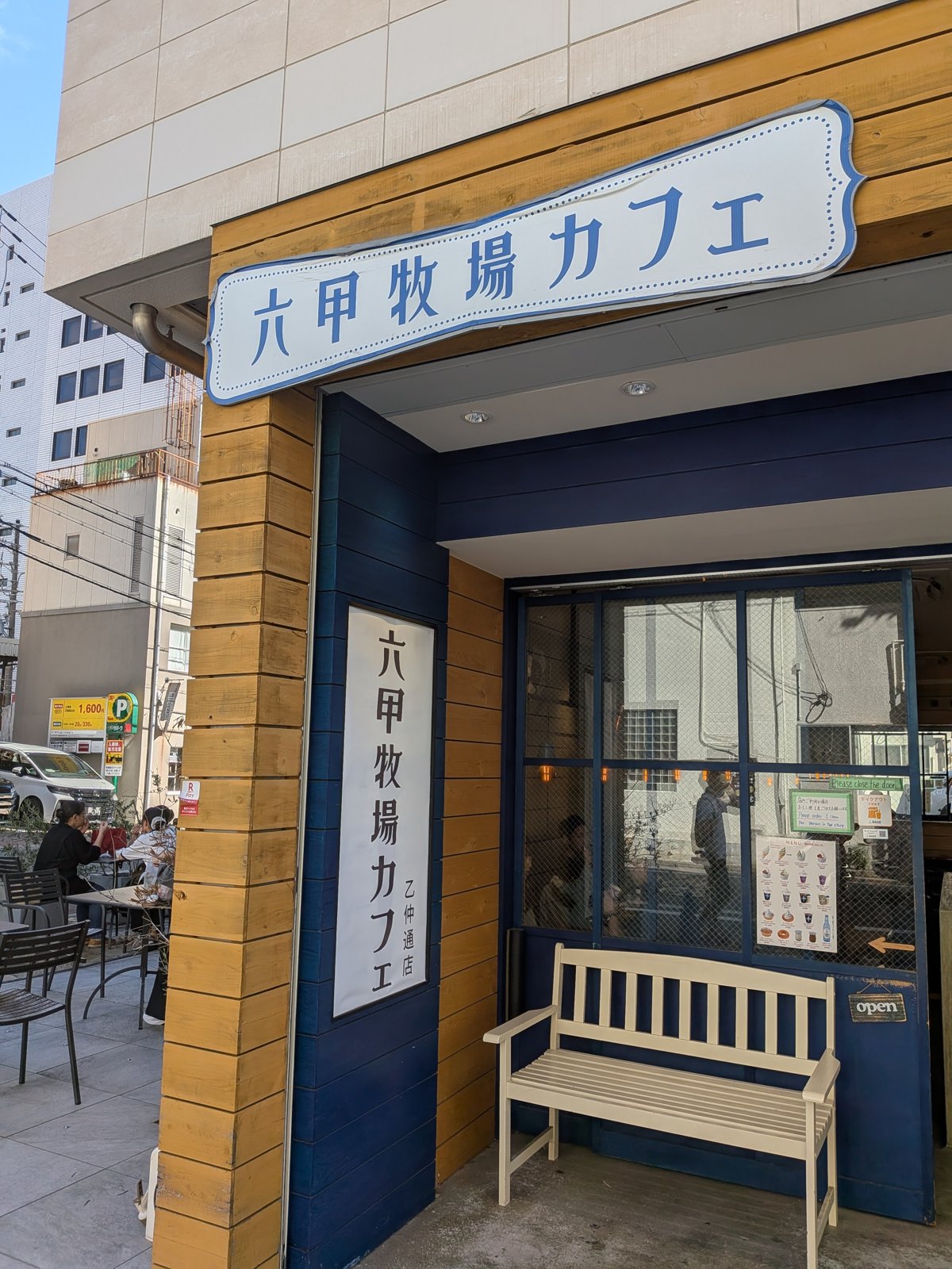 「六甲牧場カフェ」と書かれた看板のある、青い扉の店先
