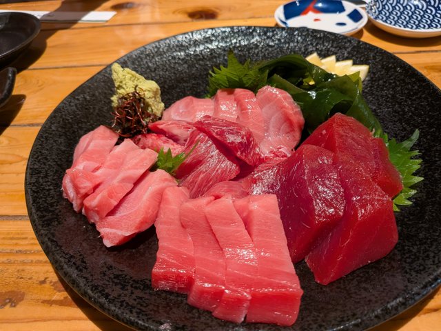 鮪6種盛りの全体。赤身から大トロまで6種類が黒い皿に並ぶ